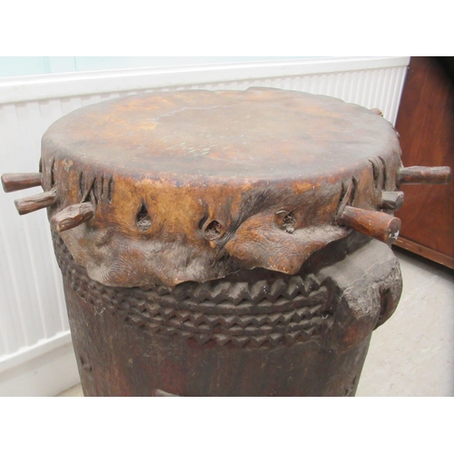 62 - An early 20thC North African tribal drum of barrel design with chip carved ornament and a stretched ... 
