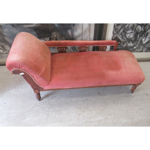 111 - A late Victorian walnut framed chaise longue, upholstered in a red fabric, raised on turned legs