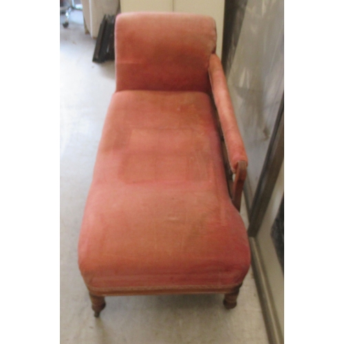 111 - A late Victorian walnut framed chaise longue, upholstered in a red fabric, raised on turned legs