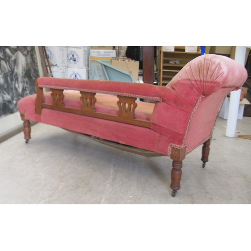 111 - A late Victorian walnut framed chaise longue, upholstered in a red fabric, raised on turned legs