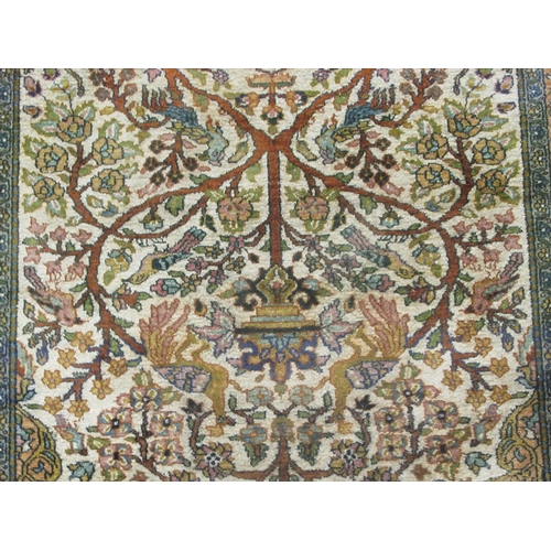 129 - A Persian tree of life design rug, on a beige and blue ground  55