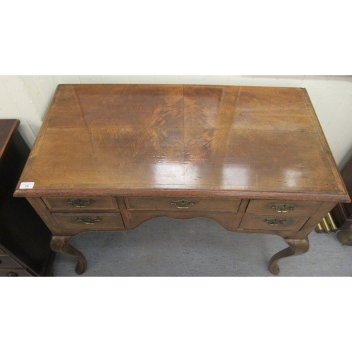 16 - A late 19th/early 20thC crossbanded mahogany and walnut, five drawer kneehole desk, raised on cabrio... 