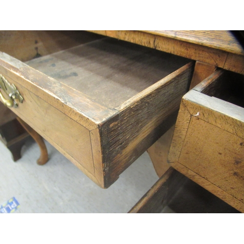 16 - A late 19th/early 20thC crossbanded mahogany and walnut, five drawer kneehole desk, raised on cabrio... 