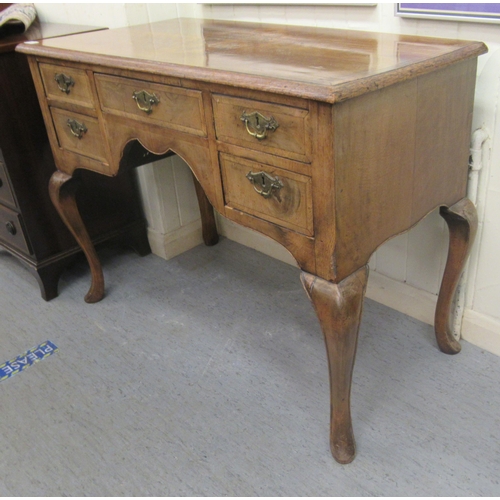 16 - A late 19th/early 20thC crossbanded mahogany and walnut, five drawer kneehole desk, raised on cabrio... 