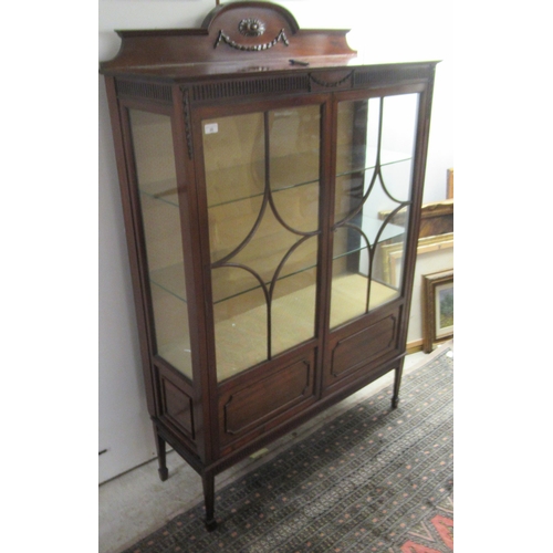 20 - An Edwardian mahogany display cabinet with a carved upstand, over two astragal glazed doors, raised ... 