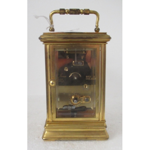 200 - A modern lacquered brass cased carriage timepiece with bevelled glass panels and a folding top handl... 