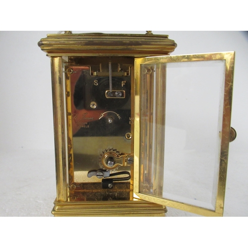 200 - A modern lacquered brass cased carriage timepiece with bevelled glass panels and a folding top handl... 