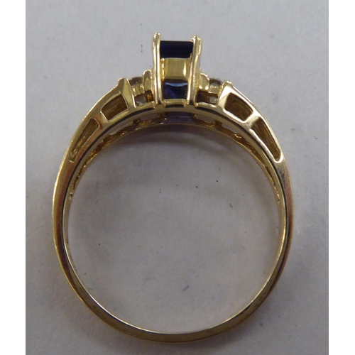 214 - A 10k gold ring, set with a central sapphire, flanked by six diamonds