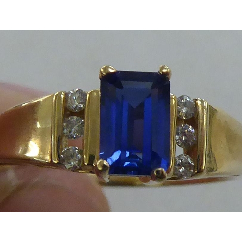 214 - A 10k gold ring, set with a central sapphire, flanked by six diamonds