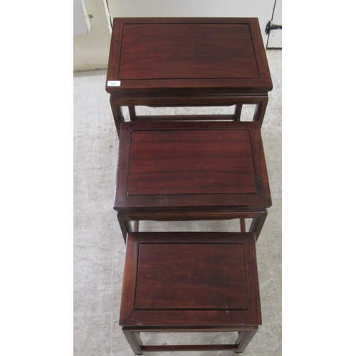 329 - A nesting set of three 20thC Chinese teak side tables, the panelled and mitred tops raised on straig... 