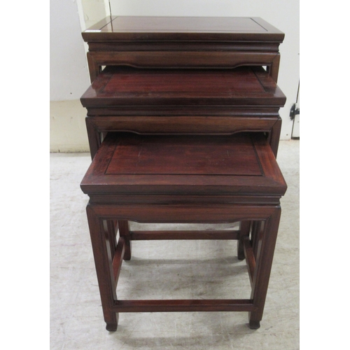 329 - A nesting set of three 20thC Chinese teak side tables, the panelled and mitred tops raised on straig... 