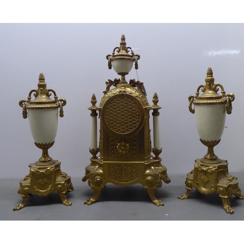 49 - A modern reproduction of a 19thC brass cased, three piece clock garniture; faced by a Roman dial  14... 