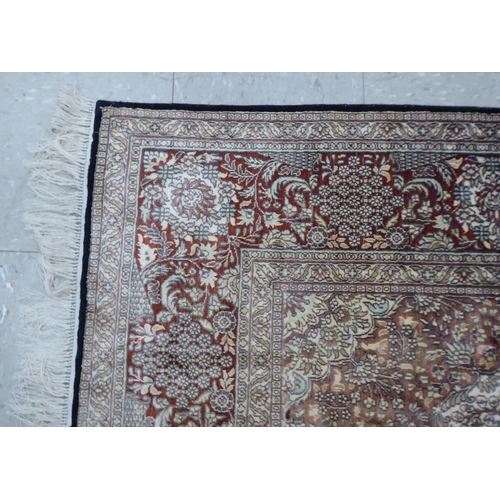 70 - A Persian woollen and silk rug, decorated with dense flora, on a gold and cream coloured ground  128... 