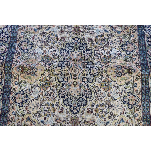 72 - A Persian woollen and silk rug, decorated with dense flora, on a blue and cream coloured ground  72