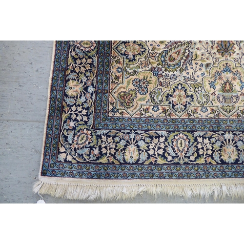 72 - A Persian woollen and silk rug, decorated with dense flora, on a blue and cream coloured ground  72