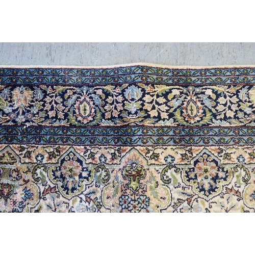 72 - A Persian woollen and silk rug, decorated with dense flora, on a blue and cream coloured ground  72