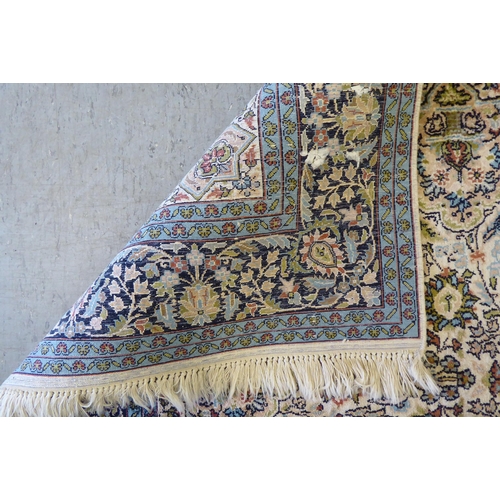 72 - A Persian woollen and silk rug, decorated with dense flora, on a blue and cream coloured ground  72