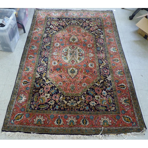 73 - A Persian woollen and silk rug, decorated with dense flora, on a peach, blue and green ground  56