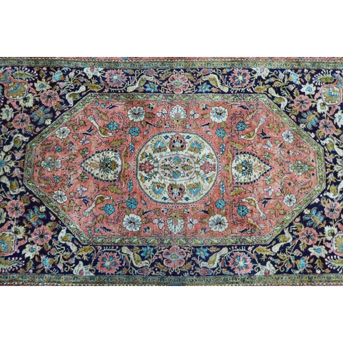 73 - A Persian woollen and silk rug, decorated with dense flora, on a peach, blue and green ground  56