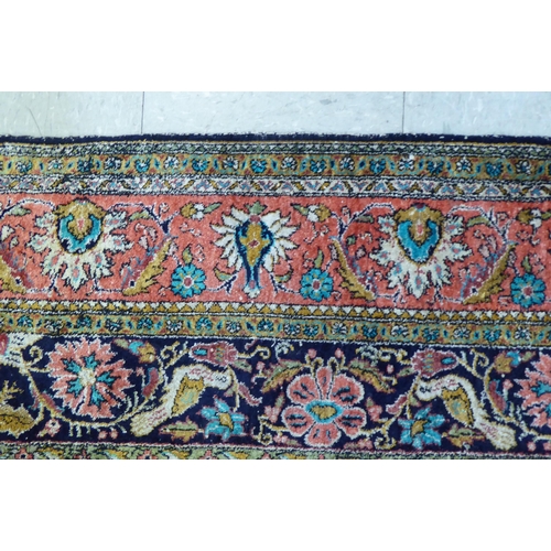 73 - A Persian woollen and silk rug, decorated with dense flora, on a peach, blue and green ground  56