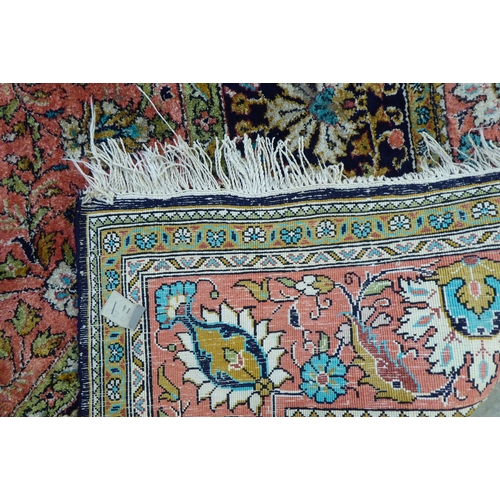 73 - A Persian woollen and silk rug, decorated with dense flora, on a peach, blue and green ground  56