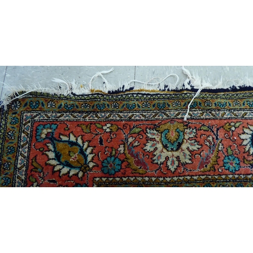 73 - A Persian woollen and silk rug, decorated with dense flora, on a peach, blue and green ground  56