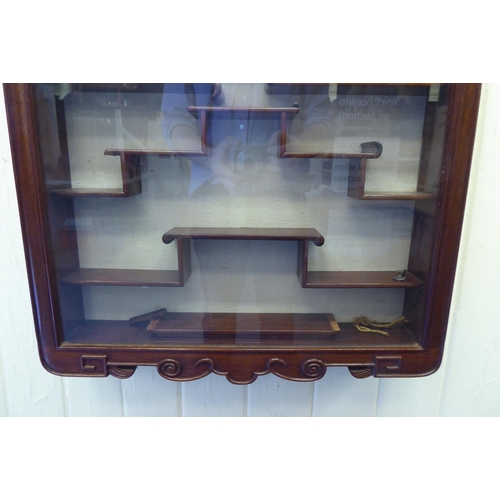 97 - A modern Japanese rosewood netsuke cabinet, having a glazed door, enclosing a tiered interior  ... 