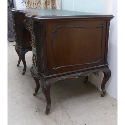 124 - An Edwardian mahogany breakfront, one piece, seven drawer, twin pedestal desk with carved ornament, ... 