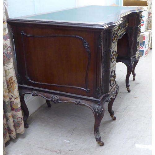 124 - An Edwardian mahogany breakfront, one piece, seven drawer, twin pedestal desk with carved ornament, ... 