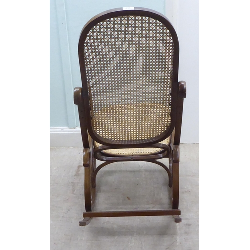 136 - A modern stained bentwood style woven cane panelled rocking chair