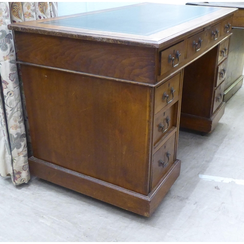 137 - An early 20thC oak nine drawer, twin pedestal desk, on a plinth and casters  30