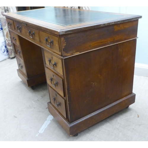 137 - An early 20thC oak nine drawer, twin pedestal desk, on a plinth and casters  30