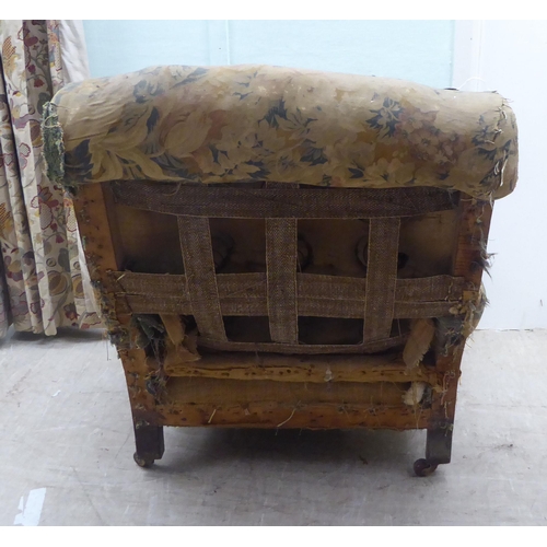 140 - A late 19thC armchair, in the manner of Howard, with a scrolled, part button upholstered back (in ne... 