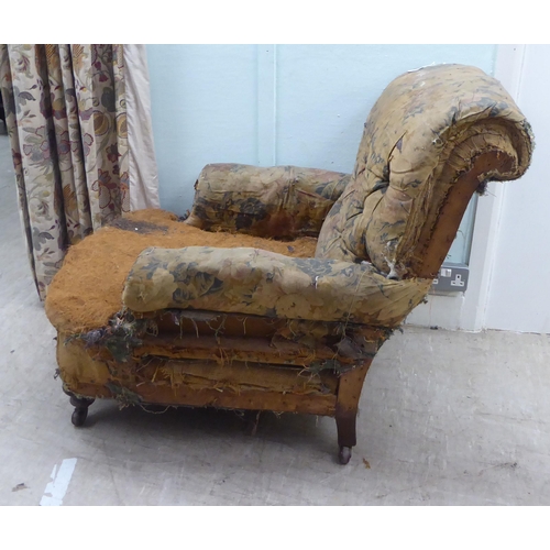 140 - A late 19thC armchair, in the manner of Howard, with a scrolled, part button upholstered back (in ne... 