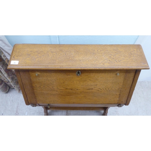 16 - An early 20thC light oak student's bureau with a fall flap, over two open shelves, raised on planked... 