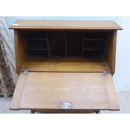 16 - An early 20thC light oak student's bureau with a fall flap, over two open shelves, raised on planked... 