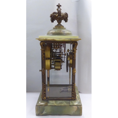 161 - An early 20thC onyx and brass framed, four glass mantel timepiece; the movement faced by a Roman dia... 