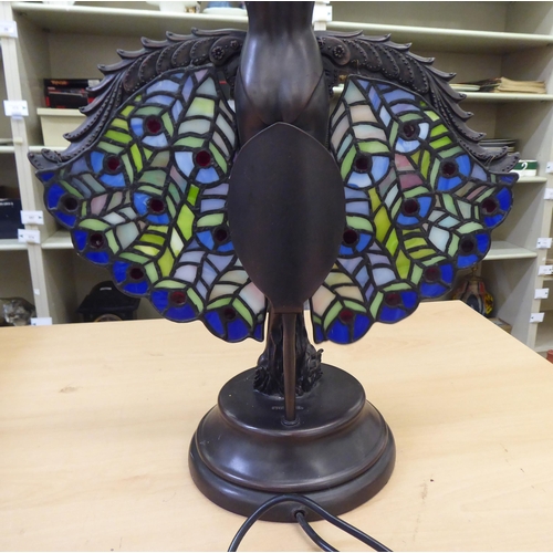 215 - An Art Deco inspired bronze effect table lamp, fashioned as a dancer holding lead glazed peacock pan... 