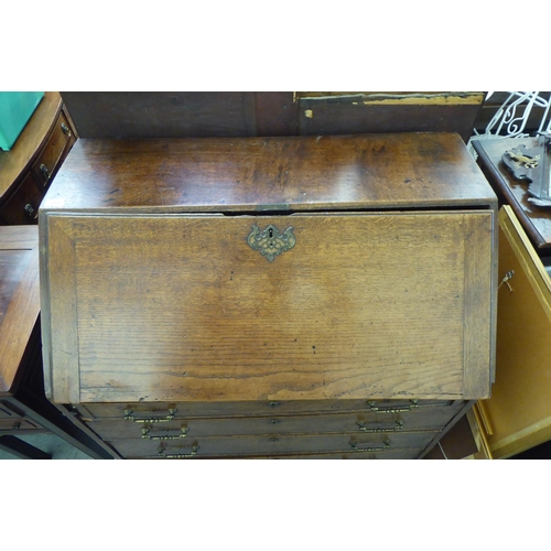 228 - A George III oak bureau with a fall flap, over four graduated drawers, on a plinth and associated st... 