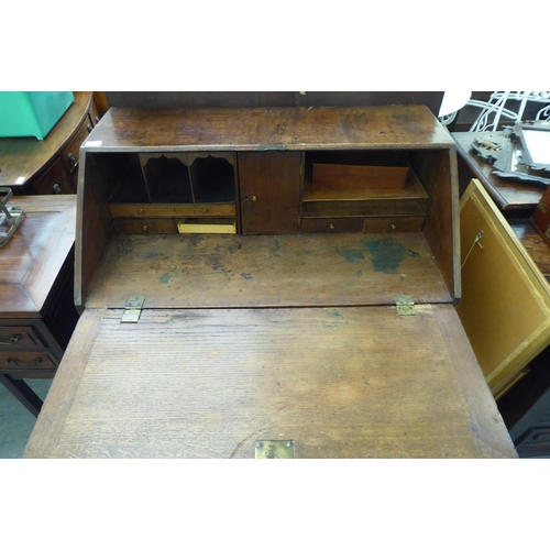 228 - A George III oak bureau with a fall flap, over four graduated drawers, on a plinth and associated st... 