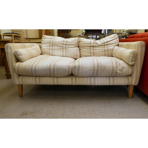 319 - A modern two person settee, upholstered in stripe patterned fabric with cushioned seats, raised on s... 