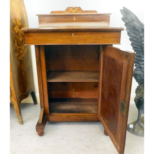 382 - A late Victorian walnut Davenport with a hinged lid, over a panelled front door, raised on turned fe... 