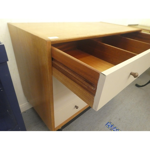 398 - A G-Plan light oak and cream coloured laminate dressing chest of four drawers, raised on turned legs... 