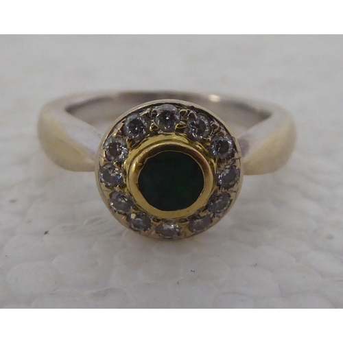 431 - An 18ct white gold Buchwald ring, set with a central round emerald, surrounded by twelve diamonds