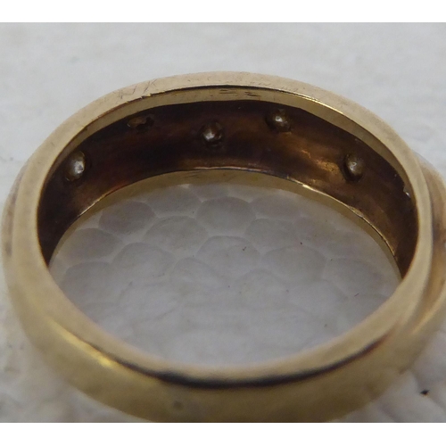 432 - A 9ct gold ring, set with six diamonds, decorated in a wavy pattern 