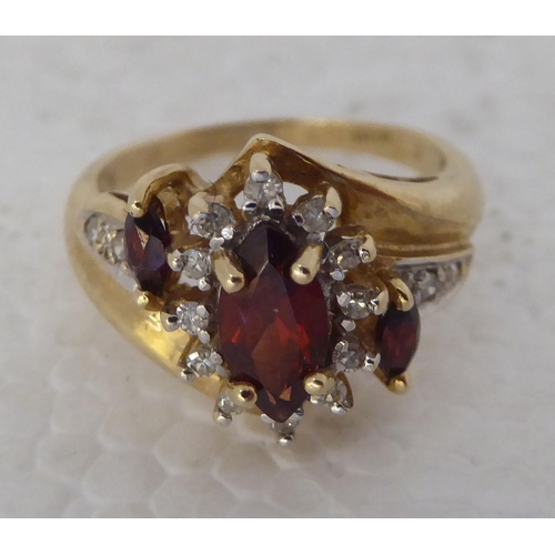 433 - A 9ct gold crossover ring, set with three marquise cut garnets and multiple diamonds 