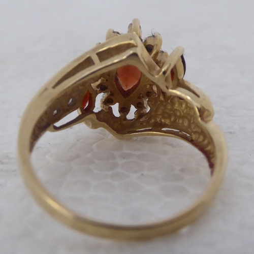 433 - A 9ct gold crossover ring, set with three marquise cut garnets and multiple diamonds 