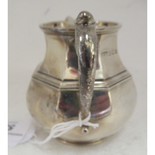 53 - A silver cream jug of bulbous octagonal form with a S-scrolled handle  London 1924 