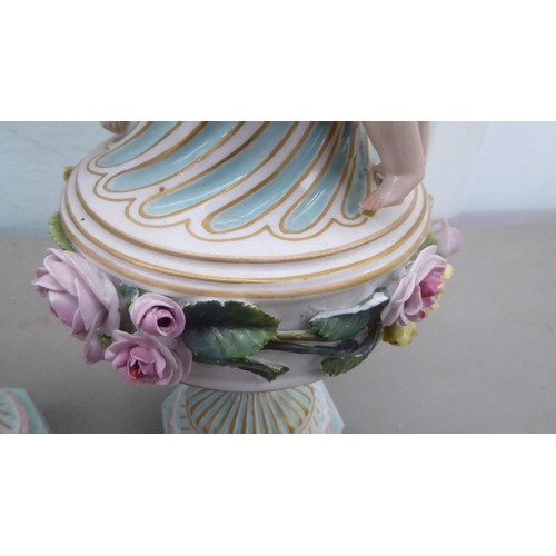 83 - A pair of late 19thC Continental encrusted porcelain pedestal vases and covers, decorated in bright ... 