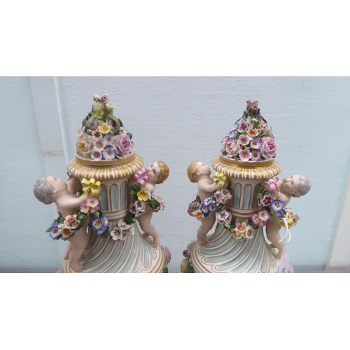 83 - A pair of late 19thC Continental encrusted porcelain pedestal vases and covers, decorated in bright ... 